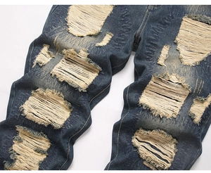 Detail view of heavy distressed denim with frayed holes and grunge style textures