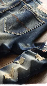 Detail view of retro distressed denim jeans with vintage stitching and torn pocket features