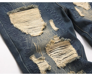 Detailed macro view of heavy distressed denim with yellow reinforced zig-zag stitching