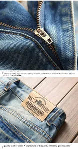 Détail de la fermeture éclair en cuivre et de l'écusson en cuir sur un jean bleu clair