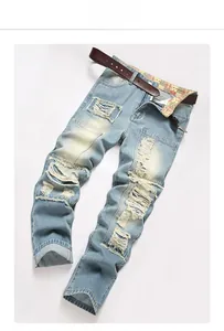 Flat lay of light blue distressed jeans with ripped details and a brown leather belt
