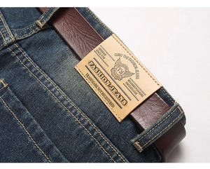 Close-up of waist detail on vintage blue jeans with leather belt and brand patch texture