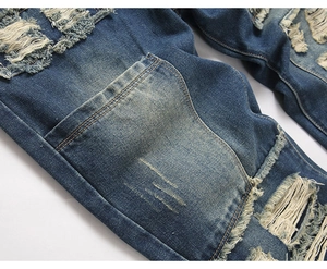 Detailed macro view of heavy distressed ripped texture and patchwork on blue denim pants
