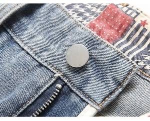 Detail view of vintage denim waist with decorative American flag patches and metal button