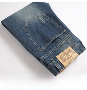 Detail of distressed dark blue denim jeans featuring vintage leather label and contrast stitching