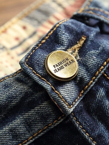 Detail of vintage denim jeans featuring bronze metal button and contrast yellow stitching