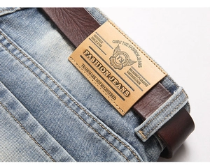 Detailed close-up of light blue denim waist with brown leather patch and contrast stitching