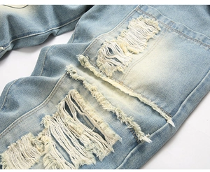 Detailed macro shot of heavy distressed ripped texture on light blue wash denim jeans