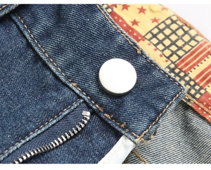 Macro detail of silver metal button and zipper on vintage patchwork jeans with patterned lining