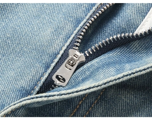 Detailed close-up of premium metal zipper and light blue denim fabric on men's jeans