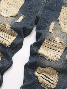 Vintage punk distressed denim jeans with frayed holes and zig-zag stitching detail
