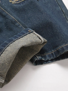 Men's vintage distressed jeans with orange stitching detail and cuffed denim hemline