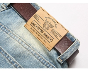 Close-up of light blue denim waist with brown leather belt and embossed brand patch