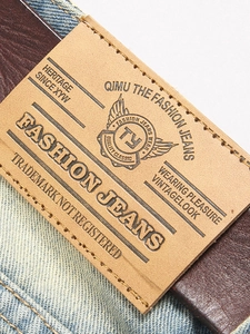 Close-up of vintage leather waist patch and belt on light blue distressed denim jeans
