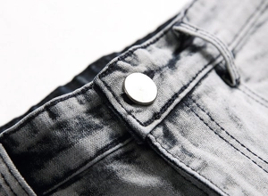 Dettaglio macro della cintura in denim grigio lavato con bottone in metallo e cuciture rinforzate