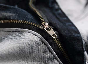 Dettaglio della cerniera alla caviglia e tessuto denim bicolore lavato su jeans da uomo