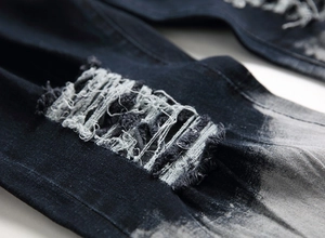 Dettaglio ravvicinato dell'effetto strappato e dei fili di cotone su jeans blu scuro
