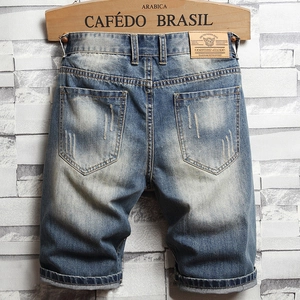 Detail of vintage blue denim shorts showing faded whiskers and leather waist patch