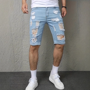 Close-up of distressed light blue denim shorts with ripped holes and fiber details