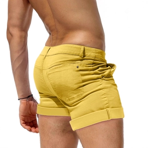 Detail view of men's slim fit bright yellow denim shorts with folded hem and back pockets