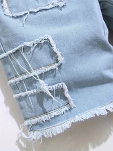 Men's light blue distressed denim shorts with ripped patchwork and frayed hem detail