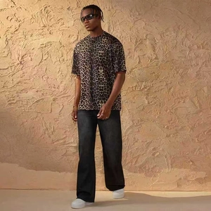 Full body shot of a man wearing oversized leopard print t-shirt and black vintage denim jeans
