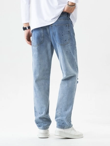 Hellblaue Herrenjeans mit schwarzen Farbspritzern und Rissen in der Rückansicht