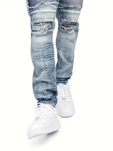 Fashionable light blue ripped jeans for men featuring distressed knee and stacked leg details