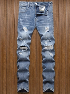 Jean homme slim bleu délavé avec genoux déchirés sur fond en bois rustique