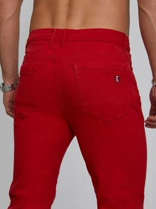 Detailed view of red slim fit trousers featuring a laurel wreath logo embroidery on the pocket