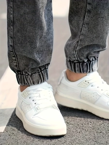 Classic white faux leather sneakers with breathable perforations and gray denim jogger pants