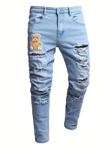 Detail view of distressed blue slim jeans with a cute teddy bear embroidery patch