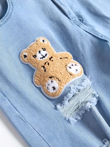 Men's slim-fit light blue distressed jeans with a cute brown plush bear patch