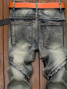 Vintage wash blue distressed straight jeans with leather belt on wood background