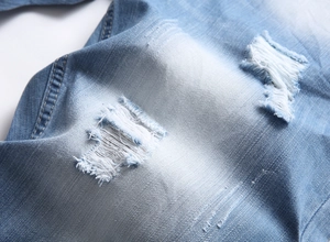 Vue macro du tissu denim bleu clair montrant des détails déchirés et une texture délavée