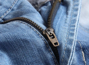 Gros plan sur la fermeture éclair en bronze des shorts en jean bleu clair pour hommes