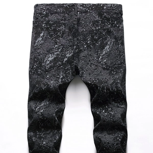 Detail of slim fit black jeans with unique white topographic lines and ink splash patterns