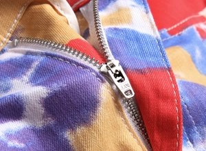 Makroaufnahme von buntem Batik-Denim-Stoff mit Metallreißverschluss und JEANS-Gravur