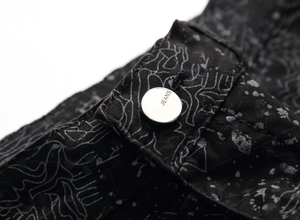 Macro detail of jeans metal button with engraving and abstract graffiti denim fabric