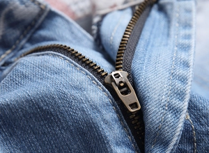 Macro shot of a vintage bronze metal zipper on high-quality blue denim shorts