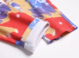 Detaillierte Makroansicht von buntem Graffiti-Batikdruck und Nähten am Jeans-Hosenaufschlag