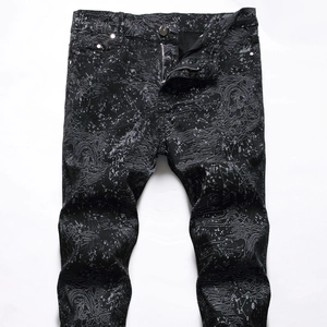 Detail of men's black street jeans with white contour print and paint splatter design