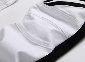 Detailed close-up of biker style jeans with white denim fabric and black side stripes
