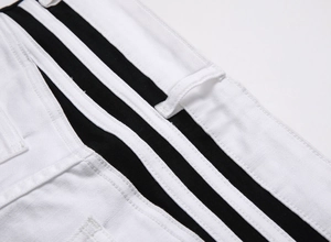 Detailed close-up of white denim waistband with black patchwork and white stitching