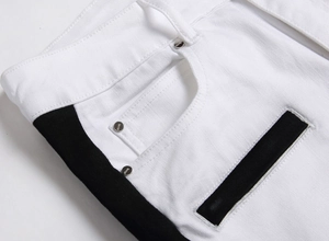 Detail view of white denim jeans waist with black side stripes and silver rivets