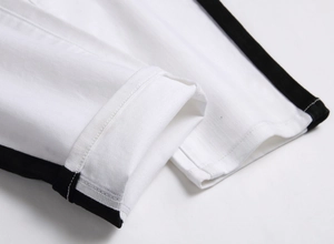 Detail shot of white stretch denim pants featuring black side stripes and hem stitching