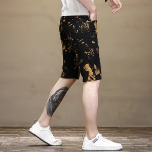 Vue détaillée du short homme noir ajusté avec imprimé doré et baskets blanches en mouvement