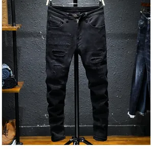 Close-up of black slim fit men's jeans featuring vintage distressed ripped patch details
