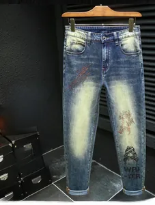 Detailed view of men's slim fit blue jeans with yellow whiskers and lightning embroidery