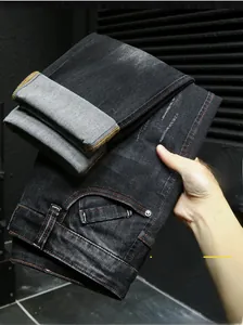 Détails du pantalon en denim gris foncé avec surpiqûres orange contrastées et bouton métal